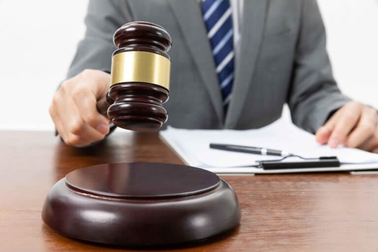 closeup-shot-person-with-gavel-hand-papers-table